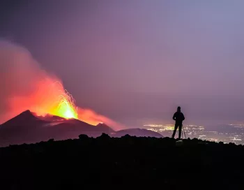 Randonneur au sommet du volcan Etna observant le feu d'une éruption active