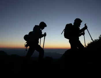 Deux randonneurs explorent les pentes basaltiques de l'Etna en Sicile avec un guide environnemental GAE certifié.